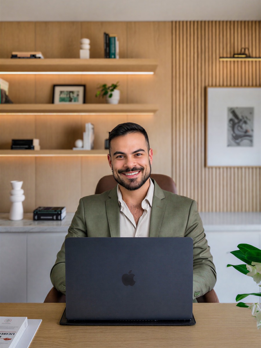 Daniel Nascimento sentado no consultório, em frente ao notebook, pronto para uma consulta por videochamada